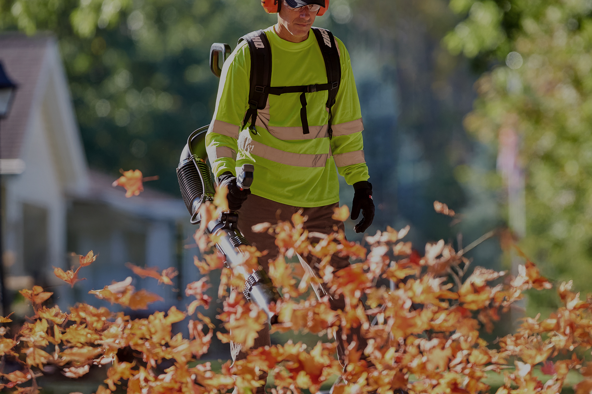 Landscaper in a high-visibility shirt clearing leaves with an Echo backpack blower